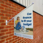 standard_flag_kit_mounted_outside_on_a_brick_wall_advertising_car_finance